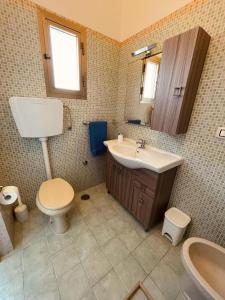 ein Badezimmer mit einem WC, einem Waschbecken und einem Spiegel in der Unterkunft Appartamento - Rosamarina in Torre Colimena