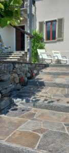 eine Terrasse mit zwei weißen Stühlen und einer Steinmauer in der Unterkunft Casa Neva in Cannobio