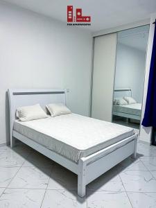 a white bedroom with a bed and a mirror at Figo Apartamentos in Praia