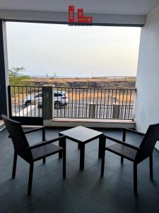 a patio with two chairs and a table and a balcony at Figo Apartamentos in Praia