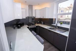 cocina con encimeras blancas, fregadero y ventana en A Beautiful 2 Bedroom Apartment with outdoor space, en Blackpool