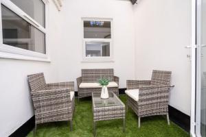 un patio con sillas de mimbre y una mesa con jarrón en A Beautiful 2 Bedroom Apartment with outdoor space, en Blackpool
