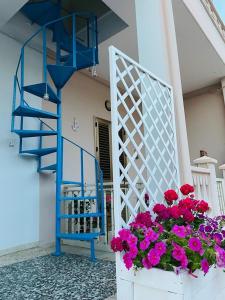 eine blaue Treppe und ein Blumenkasten mit rosa Blumen in der Unterkunft Appartamento - Rosamarina in Torre Colimena