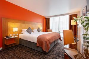 a hotel room with a bed with an orange wall at The Glasshouse in Sligo