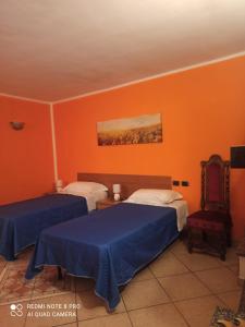 a bedroom with two beds and an orange wall at sentieri 1 in Pecetto di Valenza
