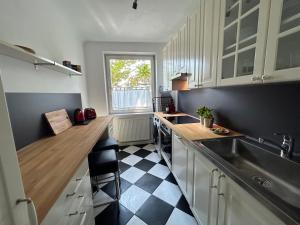 a kitchen with white cabinets and a black and white floor at Apartment Wien West in Vienna