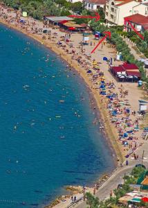 Ein Strand mit einem Haufen Leute auf Sand und Wasser in der Unterkunft Villa Gabriel in Pag