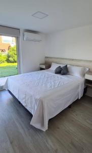 a large white bed in a bedroom with a large window at Complejo 42 in Mar Azul