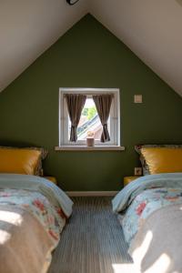a green bedroom with two beds and a window at i’dille Brīvdienu māja in Kuldīga