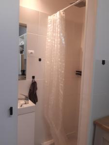 La salle de bains est pourvue d'un rideau de douche et d'un lavabo. dans l'établissement Apartament nad rzeką, à Głuszyca