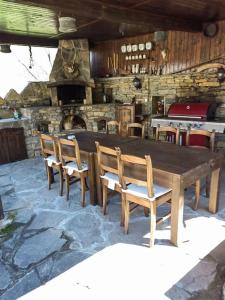 une table et des chaises en bois avec une cheminée en pierre dans l'établissement Къща за гости КИМ, à Apriltsi