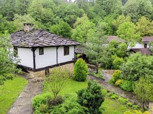una pequeña casa blanca con techo en un jardín en Къща за гости КИМ en Apriltsi