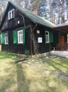 une maison noire avec des fenêtres vertes et une cour dans l'établissement Fantastyczny dom w lesie, à Długosiodło