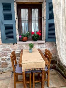 a wooden table with two chairs and a window with flowers at Ayvalık Palacitta Guesthouse in Ayvalık