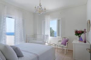 a white bedroom with a bed and a chandelier at Beachfront villa Coco in Karafotaíika