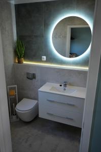 uma casa de banho com um WC, um lavatório e um espelho. em Domki Luan Village em Władysławowo