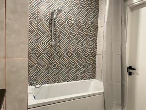a bath tub in a bathroom with a patterned wall at Електрика 24 на 7 кондиціонер Bordo city center apartment двокімнатні апартаменти в центрі міста in Poltava +9 photos