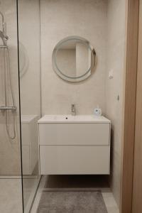 La salle de bains est pourvue d'un lavabo blanc et d'un miroir. dans l'établissement Vesiroosi Apartments - Apartment 2, à Pärnu