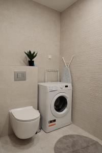 uma casa de banho com uma máquina de lavar roupa e um WC em Vesiroosi Apartments - Apartment 2 em Pärnu