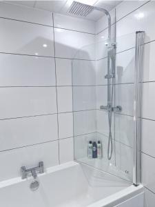 y baño de azulejos blancos con ducha. en Flat in Hamilton, South Lanarkshire, en Hamilton