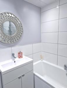 Baño blanco con lavabo y espejo en Flat in Hamilton, South Lanarkshire, en Hamilton