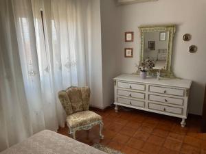 a bedroom with a dresser and a chair and a mirror at Casa Rosalina Sardinia Italy in Luogosanto