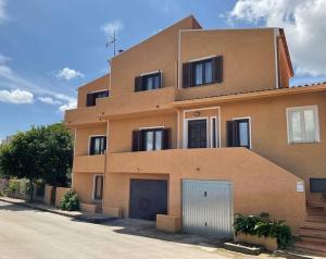 un bâtiment marron avec deux portes de garage dans une rue dans l'établissement Casa Rosalina Sardinia Italy, à Luogosanto
