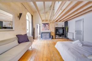 een woonkamer met een bank en een televisie bij Le 22 - Magnifique appartement en plein cœur des Chartrons in Bordeaux