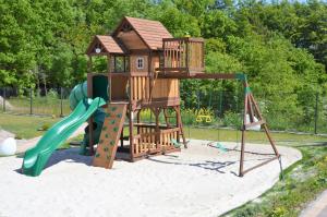 un parque infantil con una casa en el árbol y un tobogán en Domki Luan Village en Władysławowo