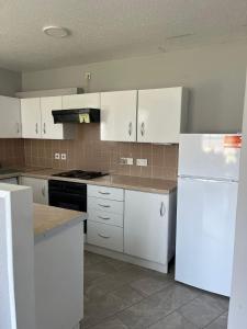 a kitchen with white cabinets and a white refrigerator at Armada Cottages Bundoran in Bundoran