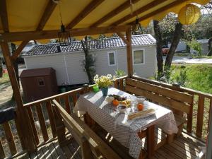 a table on a deck with food on it at Mobile home 6 places camping 5 Vacances Gorges de lArdeche in Lagorce
