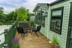 a green house with a wooden deck with a table and chairs at Treetops in Lamplugh