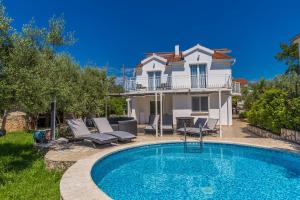 a villa with a swimming pool in front of a house at Holiday Home OLIVE GARDEN in Brzac