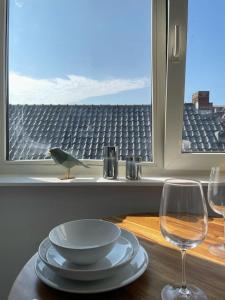 une table avec une plaque, deux verres et un oiseau sur une fenêtre dans l'établissement Appartement in Centrum Alkmaar, à Alkmaar