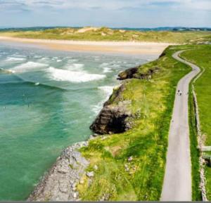 a road next to a beach and the ocean at Armada Cottages Bundoran in Bundoran