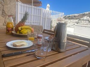 een houten tafel met een bord met eten en een ananas bij Modern Duplex apartment near swimming pool in Mogán