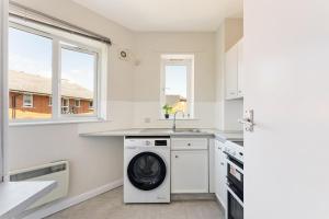 a white kitchen with a washing machine in it at Stunning aparment in Canada Water in London
