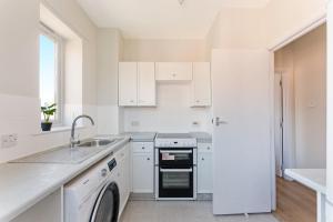 a white kitchen with a sink and a dishwasher at Stunning aparment in Canada Water in London