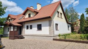 a white house with a red roof at Wakacyjny dom nad jeziorem 16 osób Holiday house in Szałstry
