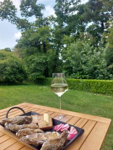 um copo de vinho branco e alguma comida numa mesa em L'échappée, Chambres et Tables d'hôtes em Saint-Fiacre