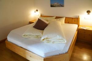 Schlafzimmer mit einem Bett mit weißer Bettwäsche und Kissen in der Unterkunft Sesvennahof in Mals im Vinschgau