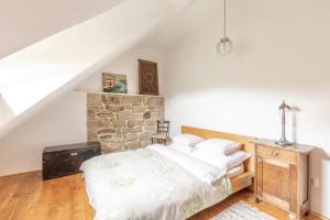 a bedroom with a bed and a stone wall at 18 century Bohemian Farmhouse in Člunek