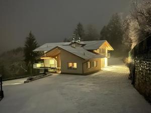 una casa con nieve en el suelo delante en Ciasa Erica - Val di Non, en Predaia
