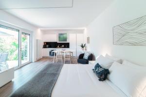 1 dormitorio blanco con 1 cama grande y comedor en La Palma 3 by Quokka 360 - studio with terrace and lake view, en Montagnola