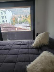 ein Schlafzimmer mit einem Bett und einem großen Fenster in der Unterkunft Para quedarse - SalePatagonia in San Martín de los Andes