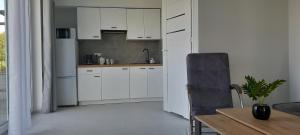 a kitchen with white cabinets and a table and a chair at Mazurskie Wzgórze BIS z basenem 1i2 in Rydzewo