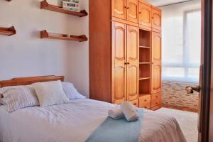 1 dormitorio con 1 cama y armario de madera en La Marina de Ajo - 12013, en Ajo