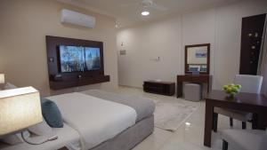 Dormitorio con cama, escritorio y TV en Anisa Residential Complex, en Salalah
