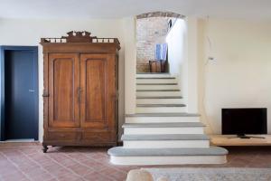 a room with stairs and a wooden cabinet and a tv at Villa Langhe in Castiglione Falletto