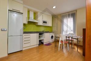 una cocina con electrodomésticos blancos, mesa y sillas en Loft en Oviedo - Ideal para 3 personas, en Oviedo
